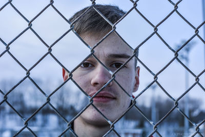 Portrait of man seen through chainlink fence