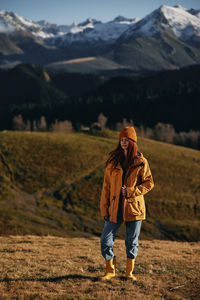 Rear view of woman walking on field against mountain