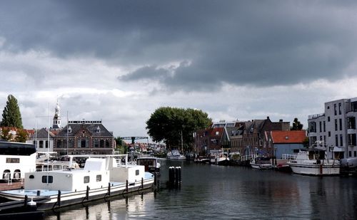 Boats moored at harbor against buildings in city