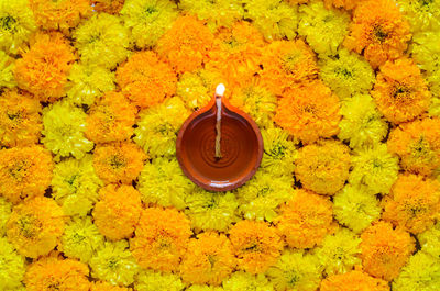 Decorative marigold flower rangoli for diwali festival with clay diya lamp.