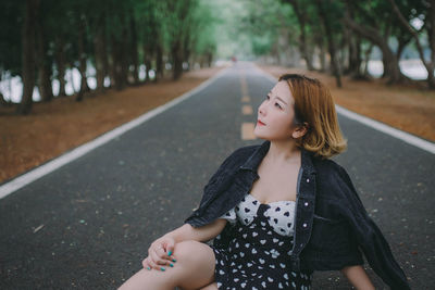 Woman looking up while sitting on road