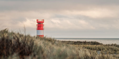 Lighthouse by sea against sky