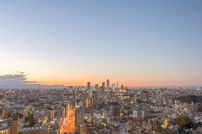 Aerial view of city buildings against clear sky during sunset