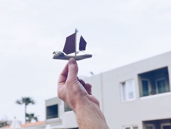 Person holding handmade small boat against sky