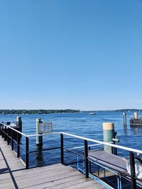 Pier over sea against clear blue sky