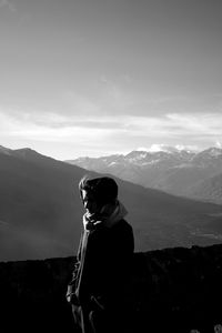 Rear view of man looking at mountains against sky