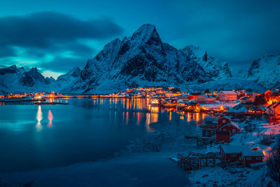 Scenic view of lake by snowcapped mountains against sky at dusk