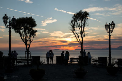 Silhouette people on beach against sky during sunset