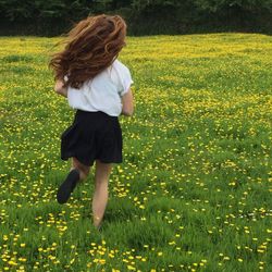 Rear view of girl on yellow flowers in field