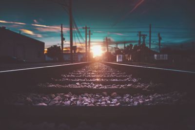 Surface level of railroad tracks against sky during sunset