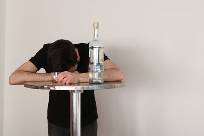 Man sitting on glass table against white background