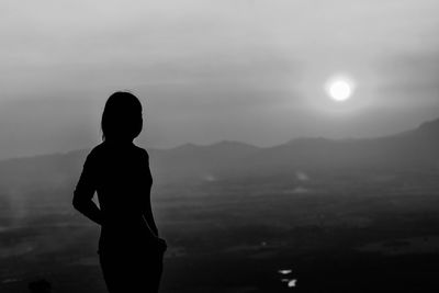 Silhouette woman standing against mountain and sky during sunset
