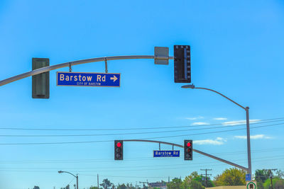 Low angle view of road signs and signal against blue sky