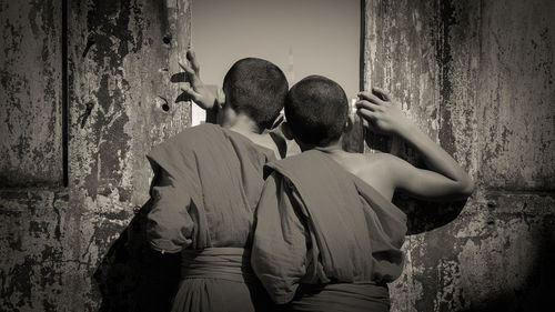 Rear view of friends standing against wall in building