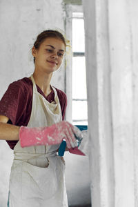 Portrait of young woman standing against wall