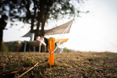 Close-up of lamp hanging on field by trees against sky