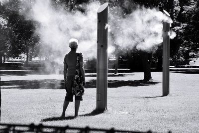 Rear view of man walking on street against trees