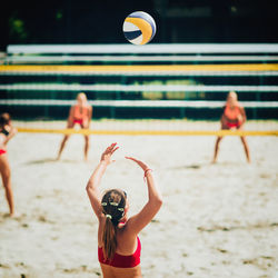 Rear view of woman playing beach volleyball