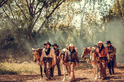 Men with horses walking on land in forest