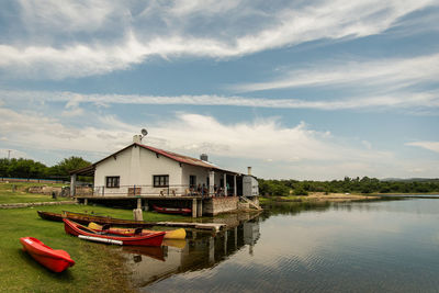 Houses by lake against sky