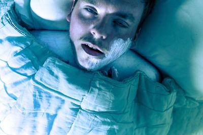 Sick man with cream on face lying down in bed