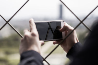 Cropped hands of man photographing by fence