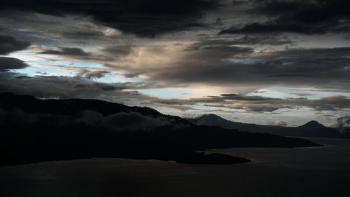 Scenic view of sea and mountains against dramatic sky