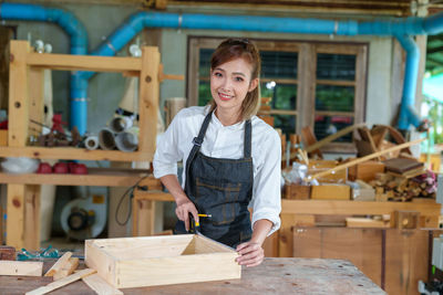 Tutor with female carpentry student in workshop studying for apprenticeship at college ,