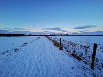 Scenic view of snow covered land against blue sky