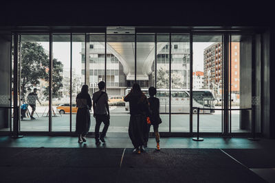 Rear view of people walking on glass window