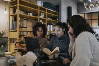 Multiracial female programmers discussing over laptop while working in startup company