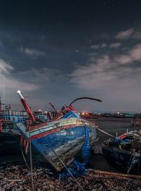 Abandoned boat moored on beach against sky at dusk