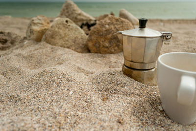 Close-up of coffee cup on beach