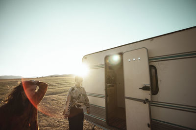 Rear view of women at train against clear sky