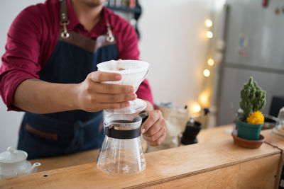 Midsection of man holding coffee cup on table