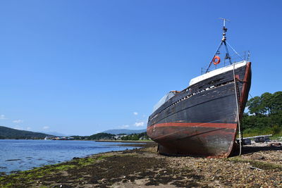 Boat moored on beach against clear sky