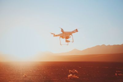 Drone flying over desert against sunset