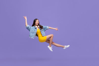 Young woman jumping against gray background