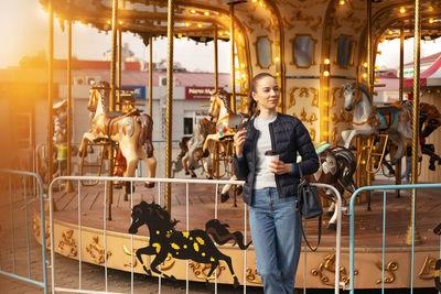 Smiling woman standing by carousel at fair