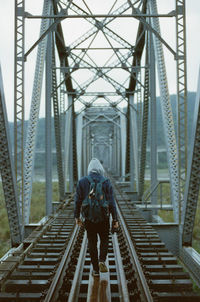 Rear view of man walking on railroad tracks