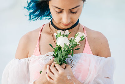 Midsection of young woman holding flower