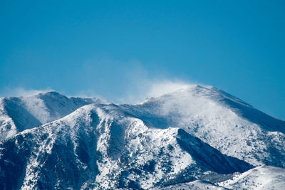 Scenic view of snowcapped mountains against clear blue sky