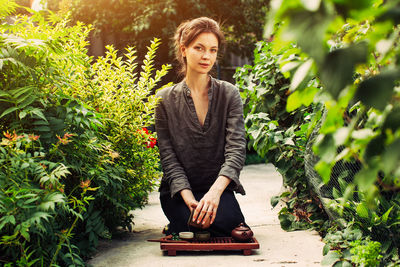 Portrait of young woman standing against plants