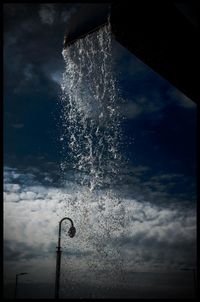 Low angle view of water splashing in sea against sky