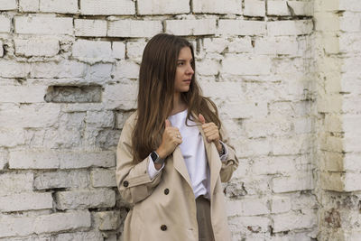 Young woman standing against brick wall