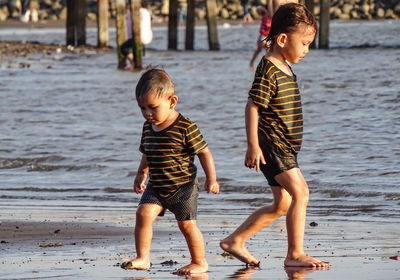 Full length of two children on beach going to opposite side of each other