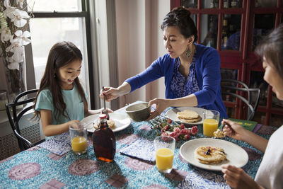 High angle view of mother serving daughter during breakfast