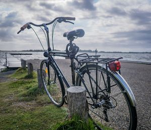 Bicycle by sea against sky