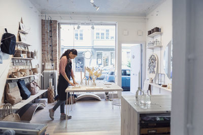 Female owner examining jewelry while standing in design studio