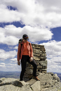 Full length of woman standing on rock against sky